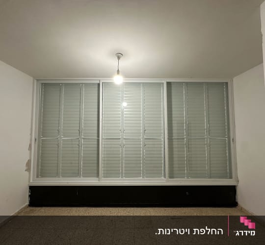 חלון אלומיניום עם תריסים סגורים בחדר